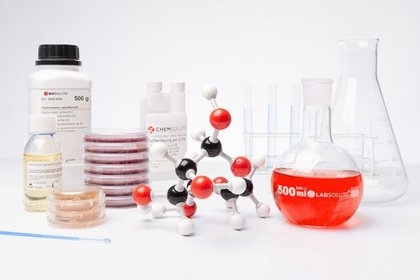 Laborgeräte und Chemikalien, darunter ein Molekülmodell, Petrischalen, Flaschen und Reagenzgläser