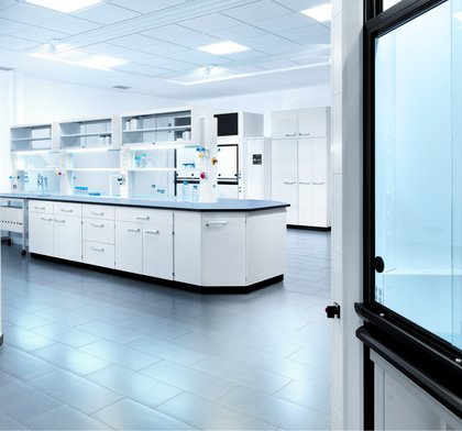 Helles steriles Labor mit moderner Laboreinrichtung von Köttermann, weißen Schränken und Arbeitsflächen und verschiedenen Laborgeräten